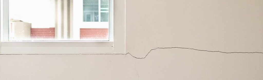 Fissure sur un mur passant sous le cadre d'une fenêtre